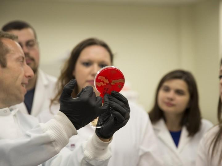 Professor holds lab sample to a group of students
